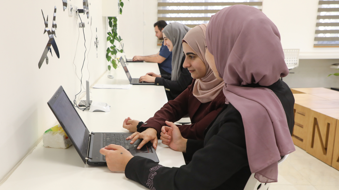 Two MENA Alliances workers looking at a laptop