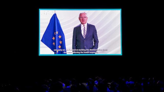 Peter Wagner in navy blue suit and stripe tie presenting his key note on Disinformation with an EU flag in background