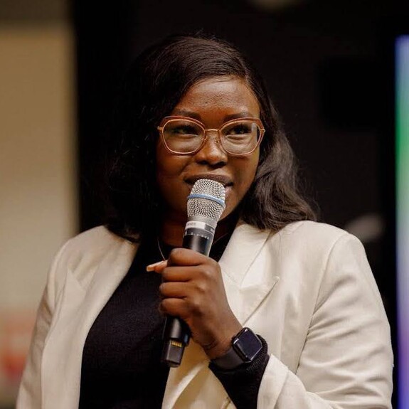 Grace Garang in white blazer and black shirt public speaking at an event